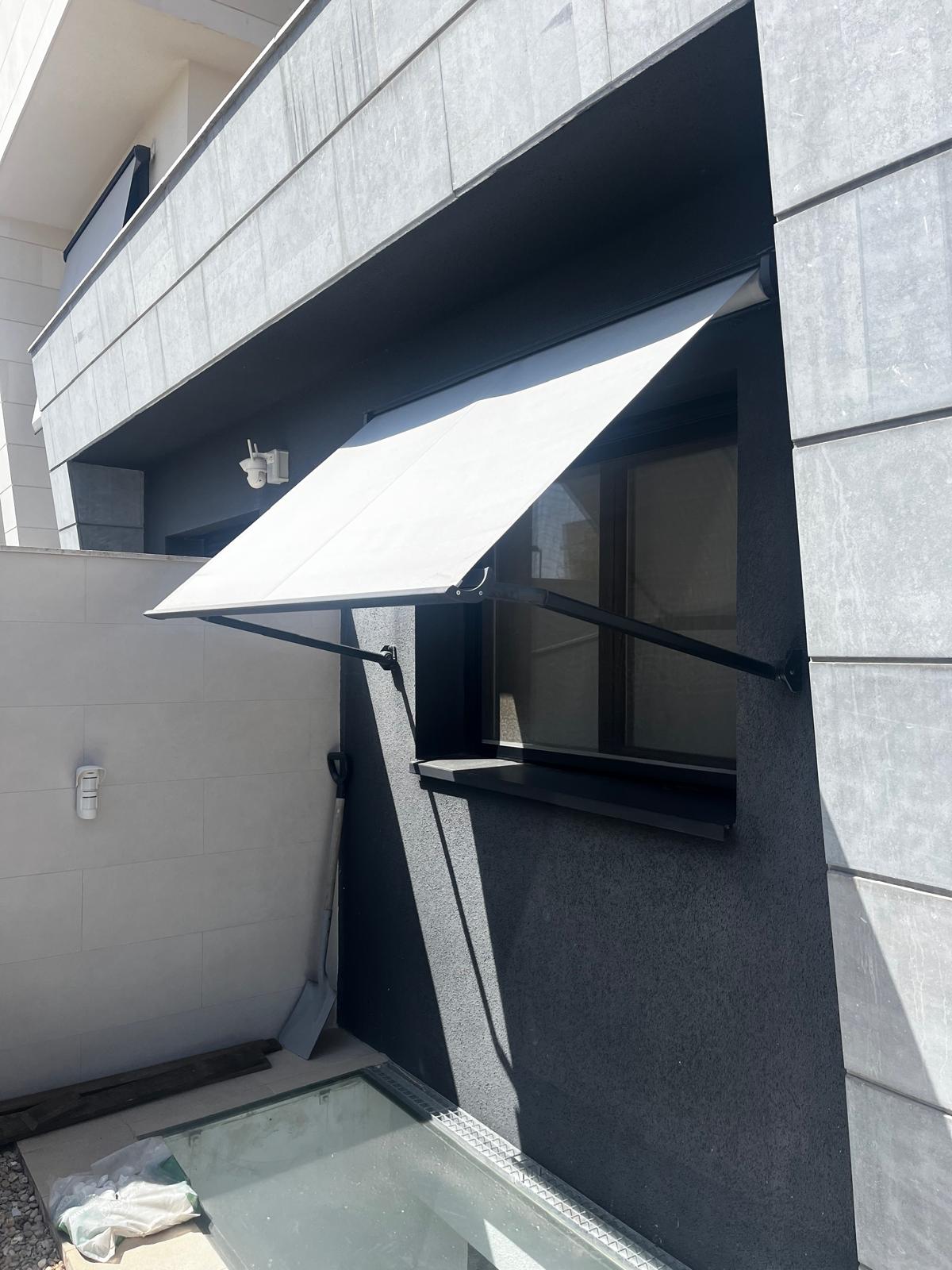 Toldo instalado en una ventana de una comunidad