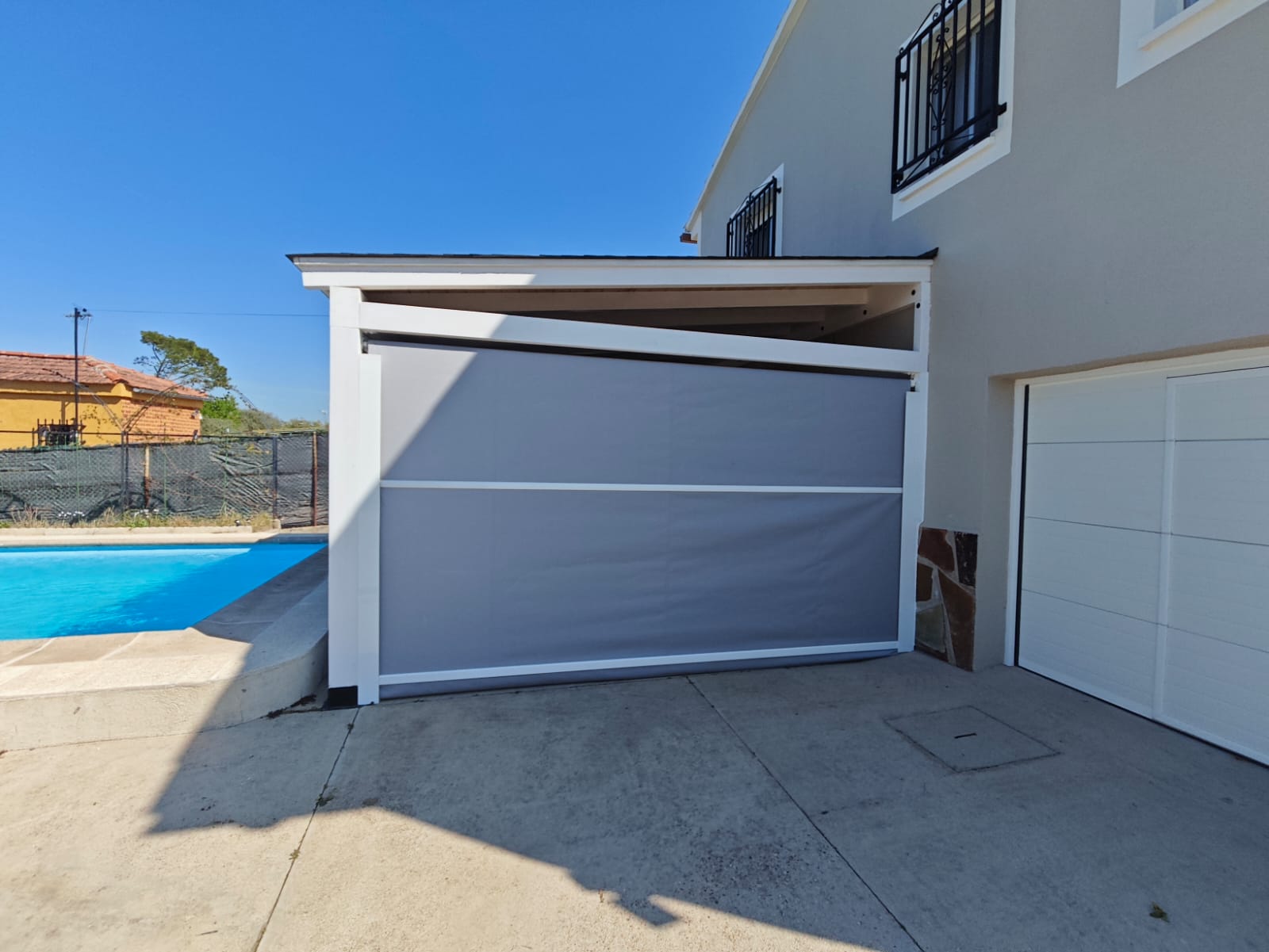 Toldo vertical gris junto a una zona de piscina