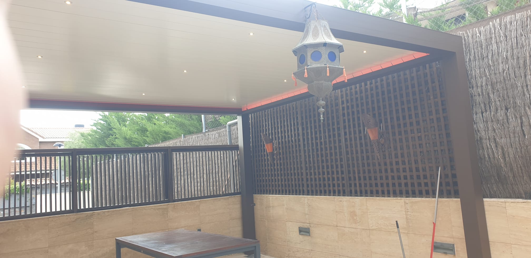 Pérgola bioclimática de aluminio marrón con lamas blancas e iluminación LED integrada