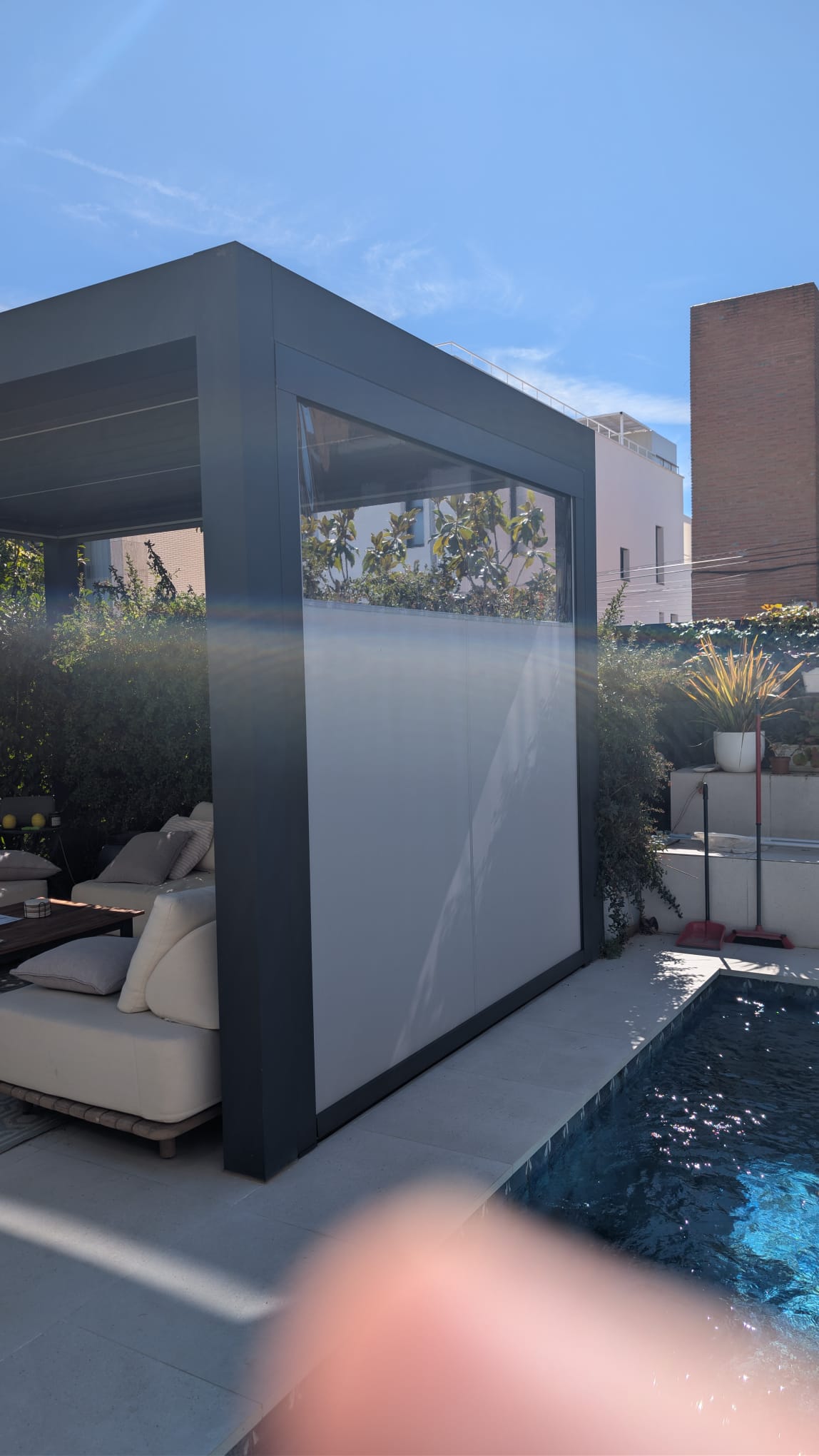 Toldo vertical junto a una pérgola en una terraza con piscina