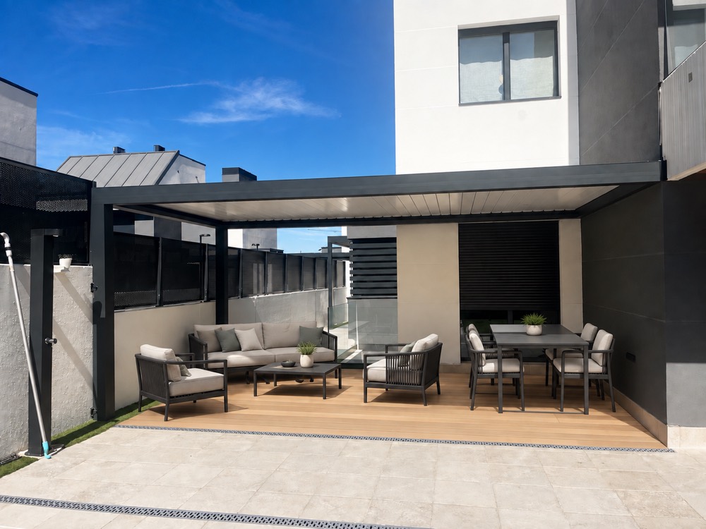 Pérgola bioclimática sobre una terraza con zona de estar y comedor