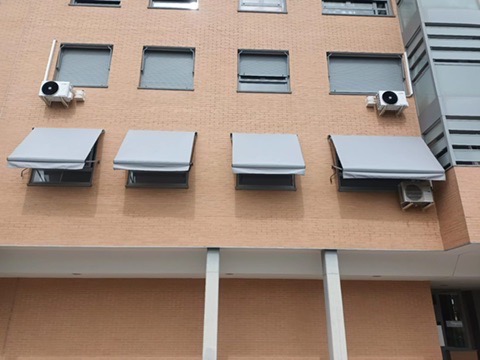 Toldos de portada grises instalados sobre cuatro ventanas de una fachada
